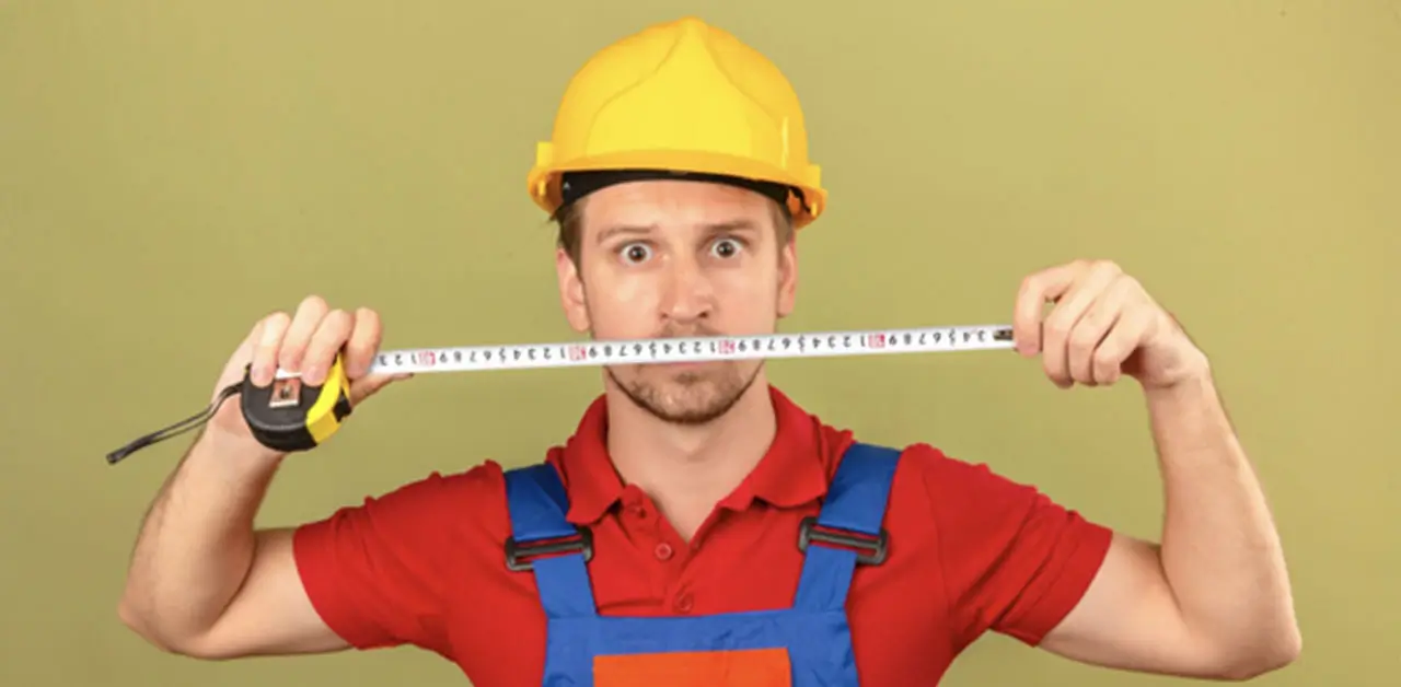 A Construction Worker In A Hard Hat Uses A Measuring Tape, Demonstrating Precision And Attention To Detail On Site
